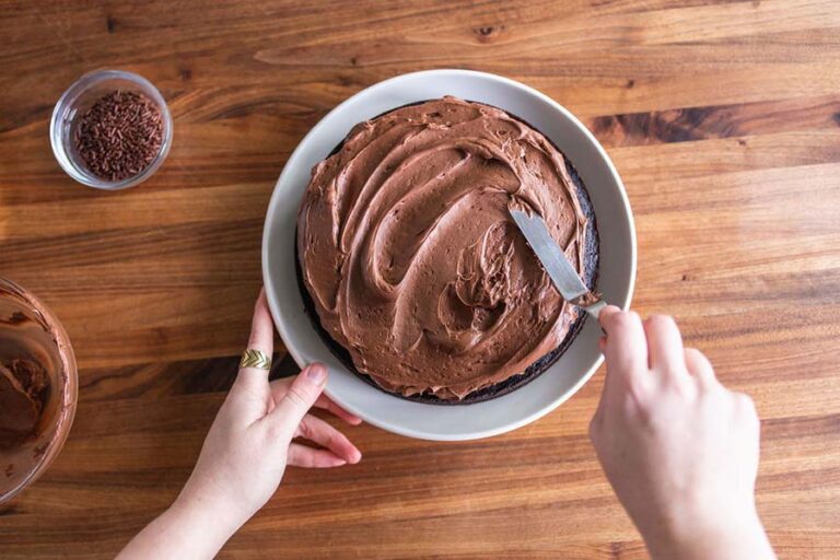 spreading chocolate frosting on cake